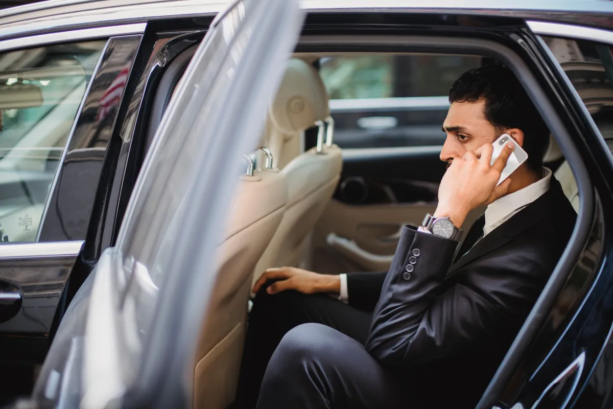 Businessman on a phone call in the back of a chauffeured car