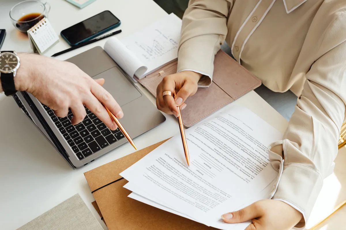 Two colleagues reviewing contract documents at a desk