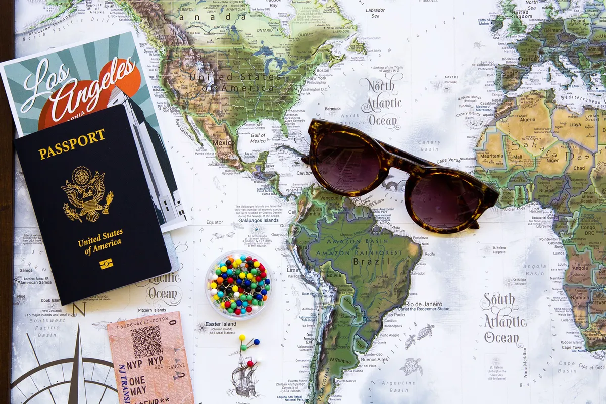 A world map with a passport, sunglasses, and a boarding pass laid out for trip planning